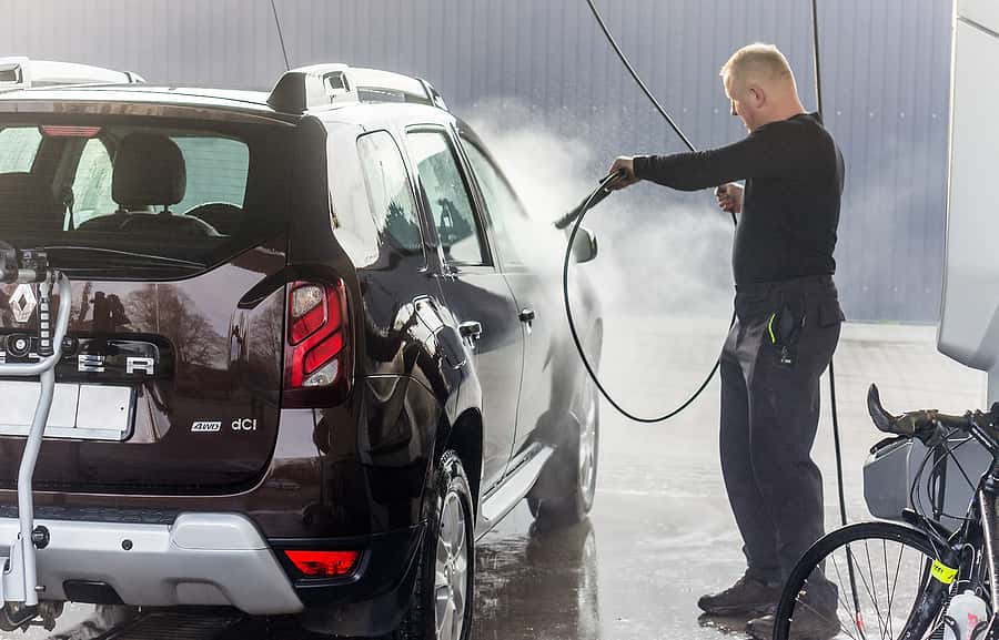 A man washes his car at a touchless car wash