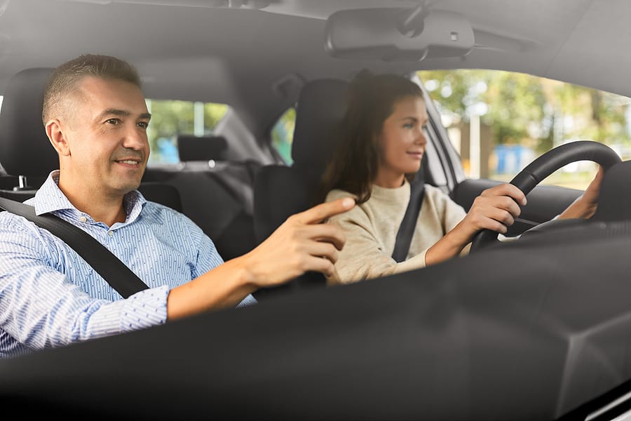 A woman test driving a used car with a salesman in the passenger seat